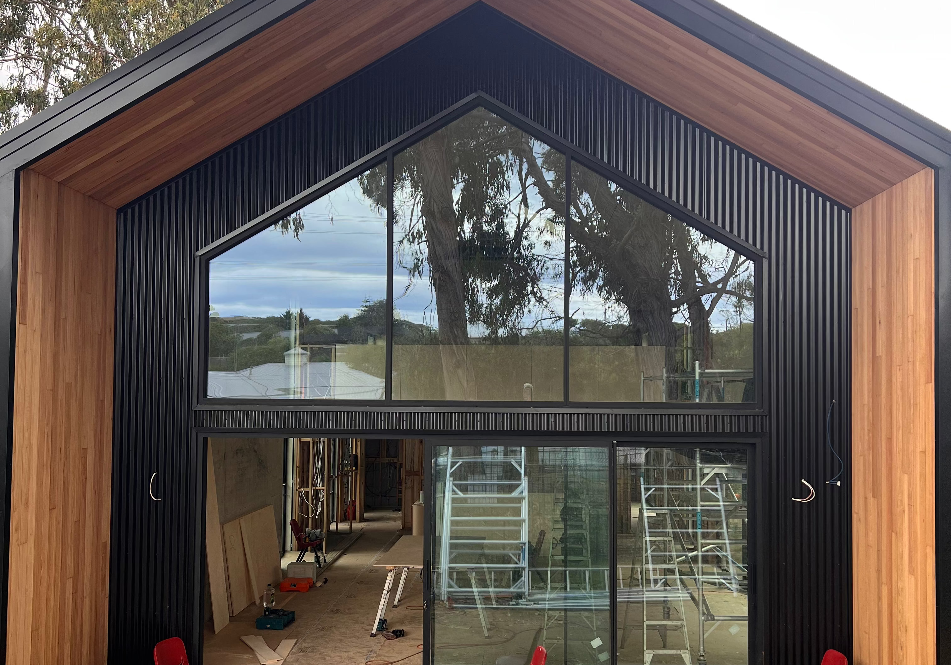 Modern Shed house under construction with large glass windows and wooden exterior.
