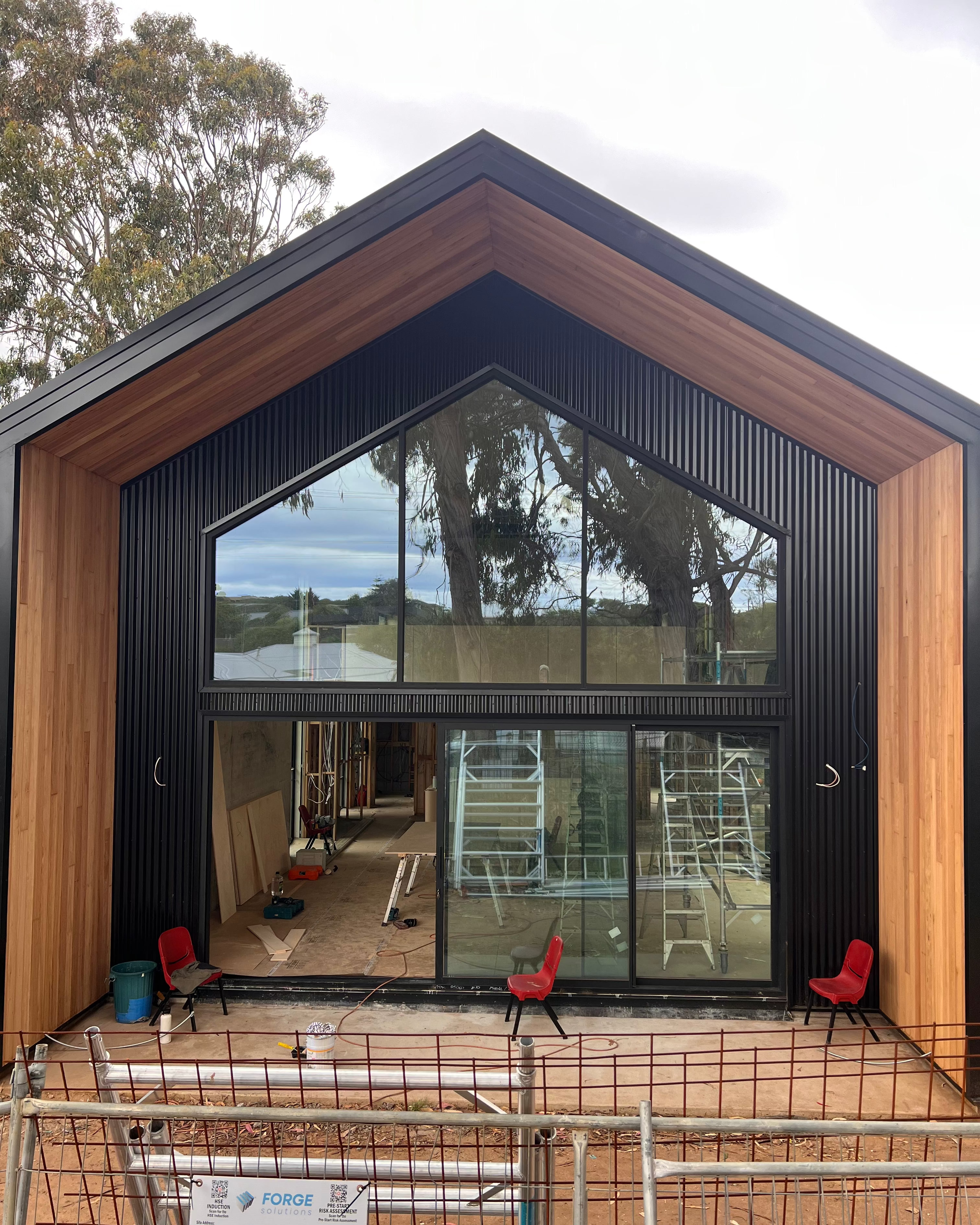 Modern Shed house under construction with large glass windows and wooden exterior.